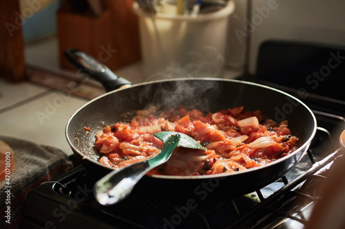 Carne en sartén con cebolla y tomate. Comida tradicional hecha en casa en un estufa por la tarde.