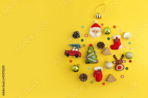 Christmas composition with copy space on yellow background of handmade felt toys flat lay. Red toy car  felt santa  deer  christmas tree  mittens on yellow background. Concept of Christmas new year