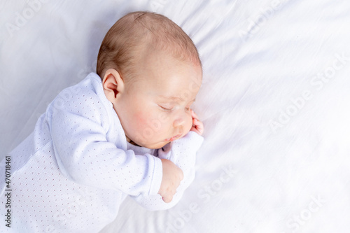 healthy sleep of a newborn baby in a crib in the bedroom on a cotton bed, portrait
