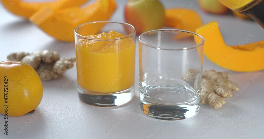 Pumpkin and ginger smoothie is poured into glasses against a background of fresh vegetables and fruits. Pumpkin and ginger smoothie is poured into glasses against a background of fresh vegetables and fruits.