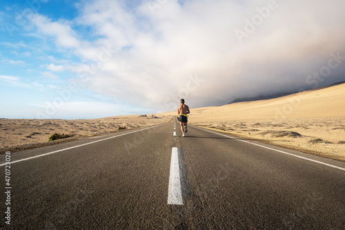 fitness person running on the road through the desert  © oscargutzo