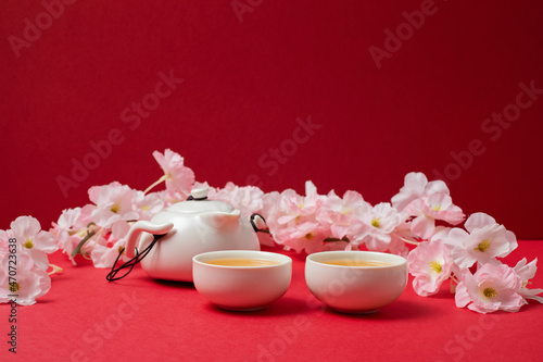 Chinese new year festival decoration over red background. Traditional lunar new year with green tea, cherry blossom.