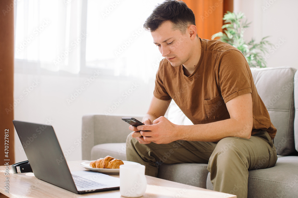 Portrait of a handsome happy blogger using his laptop during breakfast. Portrait of a handsome happy blogger using his laptop during breakfast.