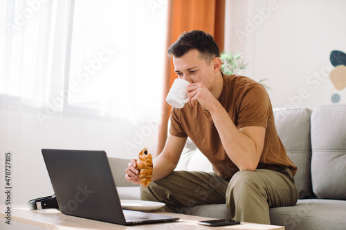 Portrait of a handsome happy blogger using his laptop during breakfast.