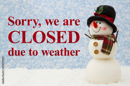 Closed due to weather sign with snowman and snow with snowy sky photo
