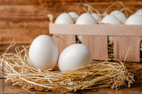 Fresh chicken eggs on hay on wooden background. Organic food concept