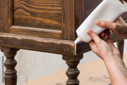 Las manos del restaurador reparan una grieta en el mueble antiguo con masilla 