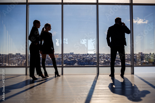 Canvas Print Two women and a man in the office enjoy the view of the city from the window of