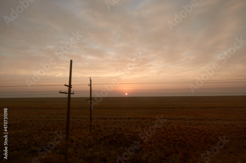 View from the train window. Sunrise in the steppe. Railway poles.
