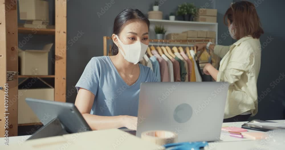 Professional attractive cheerful two young Asian lady owner teenager with casual with laptop check stock inventory product control delivery goods to customer purchase order at the cloth store at home. Professional attractive cheerful two young Asian lady owner teenager with casual with laptop check stock inventory product control delivery goods to customer purchase order at the cloth store at home.