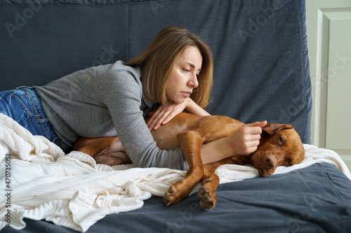 Fotografia Worried woman taking care of weakening old dog at home