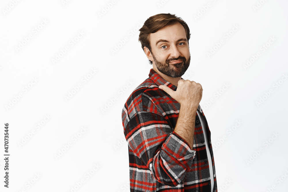 Disappointed bearded guy in checked shirt, grimacing and pointing left, showing something with dislike, standing over white background Disappointed bearded guy in checked shirt, grimacing and pointing left, showing something with dislike, standing over white background