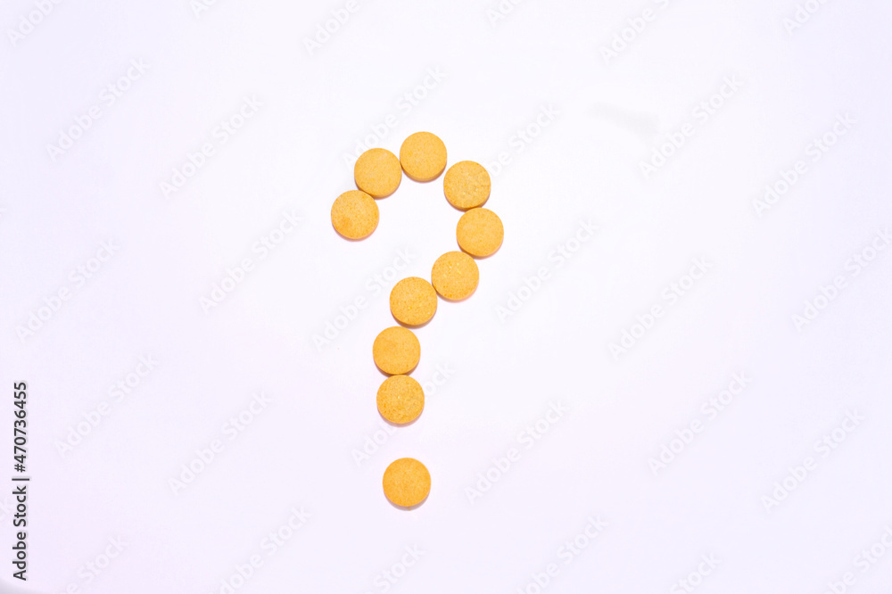 A question mark made of yellow pills. White background. Top view.