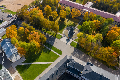 Panoramic aerial view of the Kremlin in Veliky Novgorod, golden autumn in the city, yellow treetops, a bridge over the Volkhov river, city sandy beach, a fortress.Sophia Cathedral.