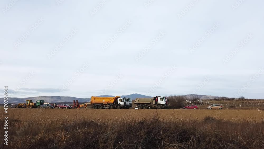 Industrial dumper trucks on highway road construction site, loading and unloading gravel and earth Industrial dumper trucks on highway road construction site, loading and unloading gravel and earth