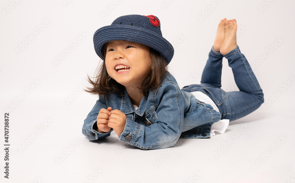 Asian smiling little girl portrait lying on floor isolated on white background. Asian smiling little girl portrait lying on floor isolated on white background.