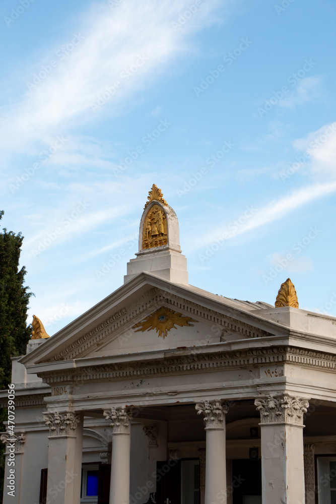 Fototapeta premium Old white church with gold motifs. church which is a landmark of city standing on the cloudy sky view.