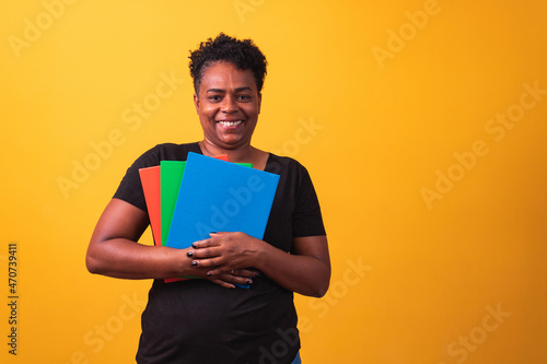 Mature student woman smiling looking at camera with space for text on yellow background. Mature black student woman photo