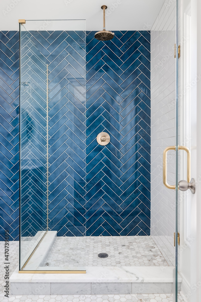 A blue single herringbone tiled shower in a luxury home with gold