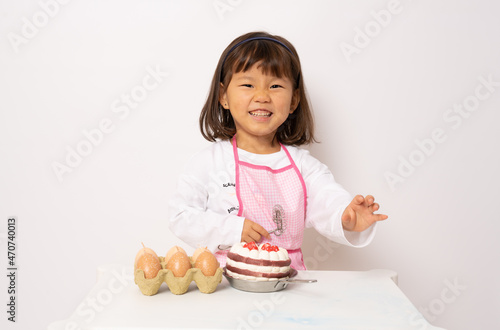 Beautiful little asian girl cooking isolate on white background