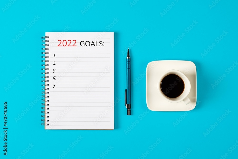 2022 goals concept banner. Notebook, pencil and a cup of black coffee isolated on blue background 2022 goals concept banner. Notebook, pencil and a cup of black coffee isolated on blue background