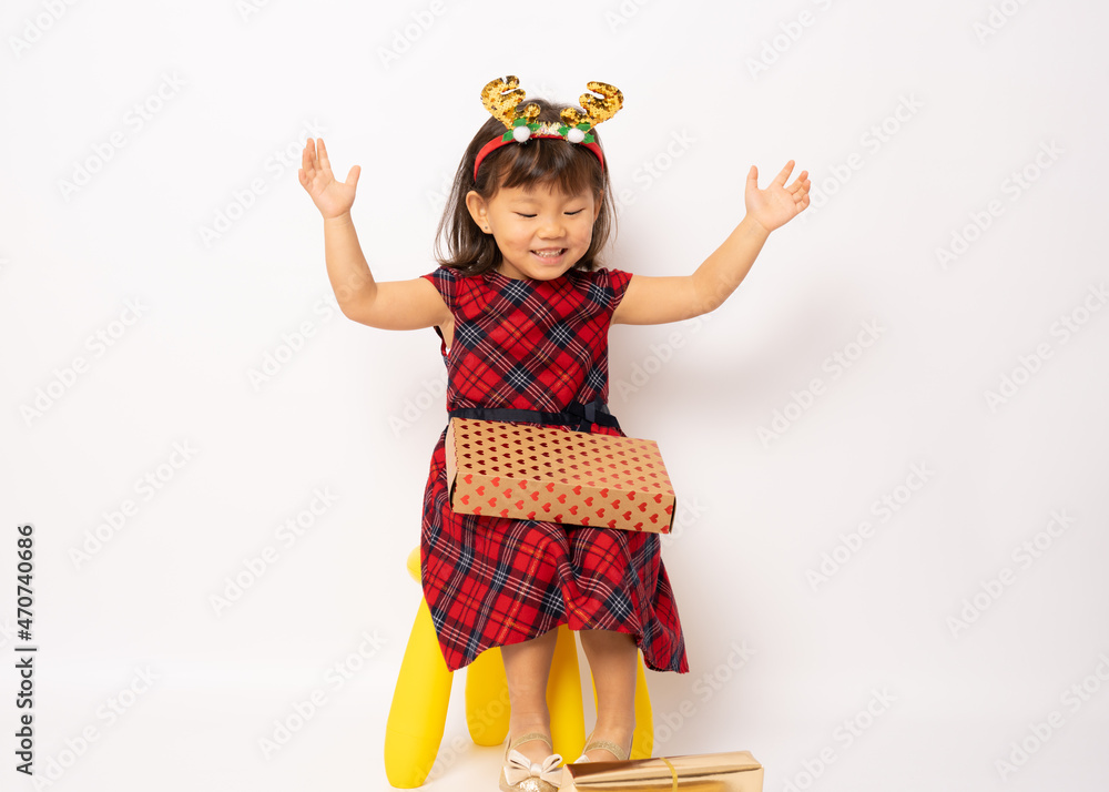 Cute smiling little asian girl in santa hat sitting with gift box isolated over white background. Cute smiling little asian girl in santa hat sitting with gift box isolated over white background.