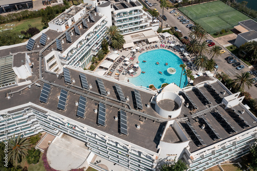 Obraz na płótnie Aerial drone photo taken on the beautiful island of Majorca in Spain showing a top down view of a hotel building apartment with solar panels on the roof and and an out door swimming pool in the summer w salonie