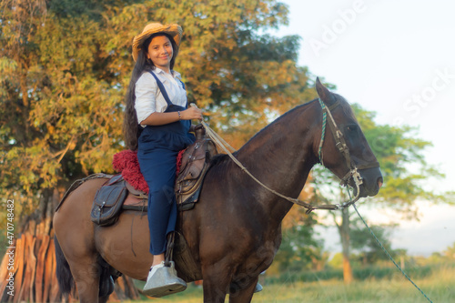 young brunette girl long black hair riding a horse in the field on a sunny day 