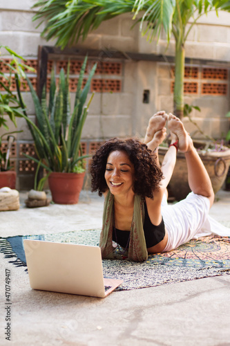 Woman lying on a yoga mat in front of a laptop on the terrace photo