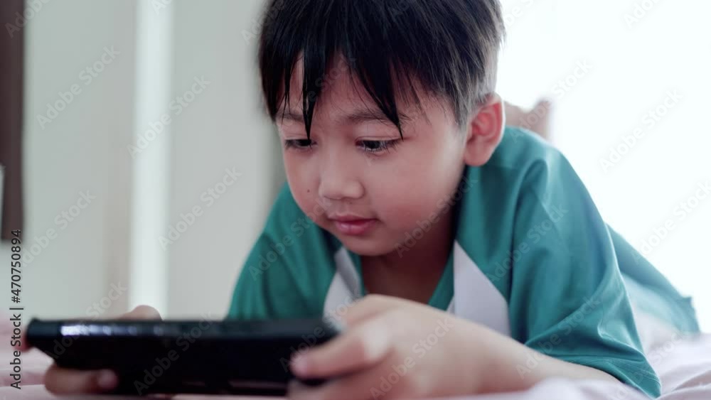 little asian boy playing games online with smartphone at home little asian boy playing games online with smartphone at home