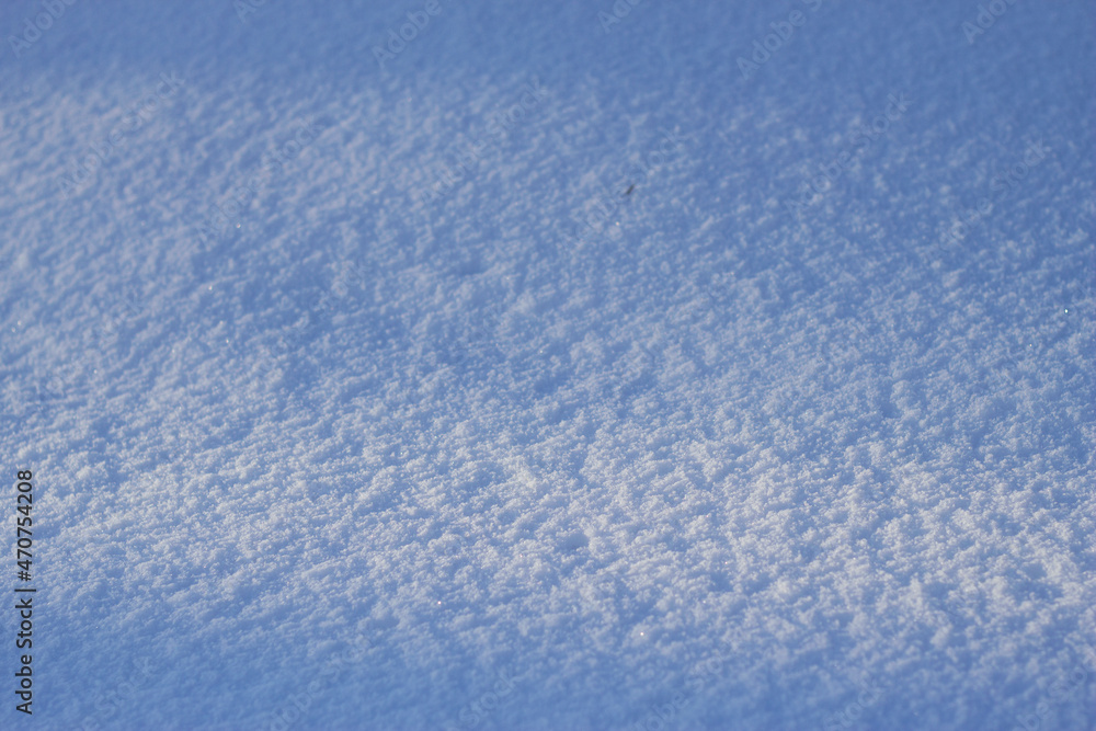 pure and textured snow surface with blue sky reflection in sunny winter day