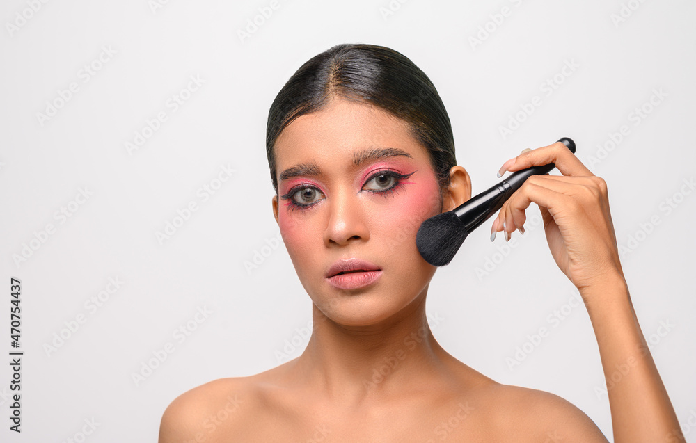 woman wearing pink makeup and holding a blush brush