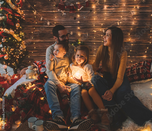 Young parenthood. Hispanic family having a pleasant time with their baby and daughter in living room decorated by christmas tree and. Portrait loving family holiday. Merry xmas and Happy New Year.
