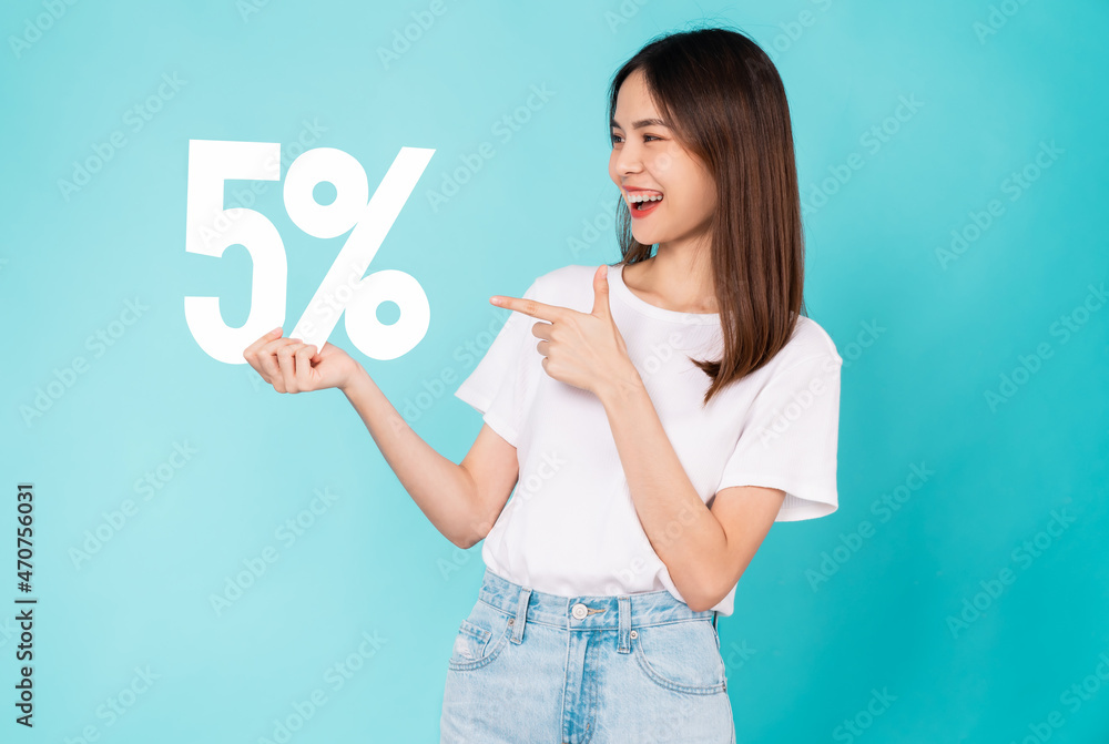 Cheerful beautiful Asian woman stand with pointing finger on hand holding 5% on light blue background. Cheerful beautiful Asian woman stand with pointing finger on hand holding 5% on light blue background.
