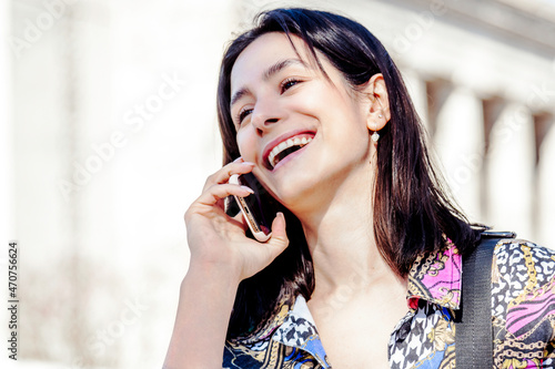 young woman talking on a cell phone in the street and smiling