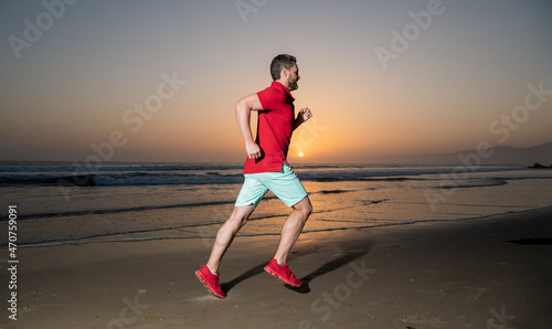 morning workout activity. healthy man running on sunrise beach. energetic summer.