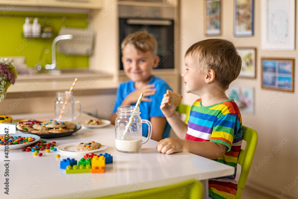 Funny male brothers eat cookies with round multi-colored sweets and drink milk. Funny male brothers eat cookies with round multi-colored sweets and drink milk.