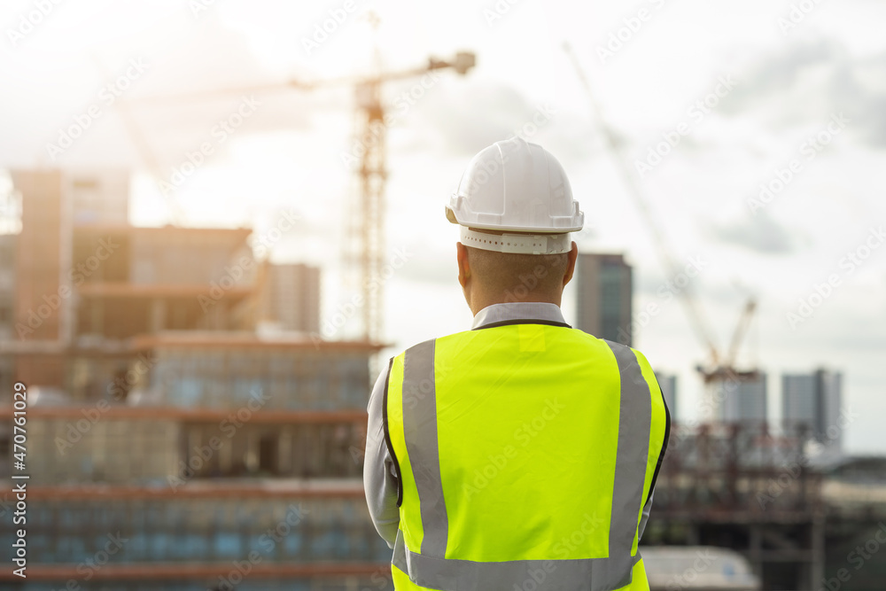 Asian engineer man or architect looking forward with white safety helmet in city construction site . Standing on rooftop building construction at capital. Asian engineer man or architect looking forward with white safety helmet in city construction site . Standing on rooftop building construction at capital.