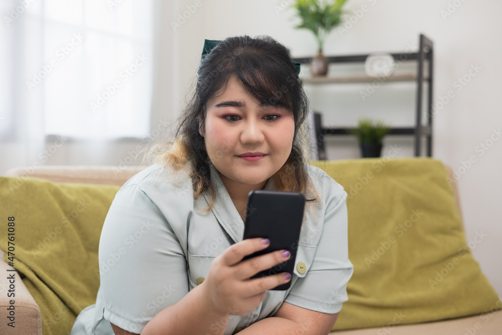 Body positive plus size woman using smartphone. Body positive plus size female lives happily and is proud of herself.