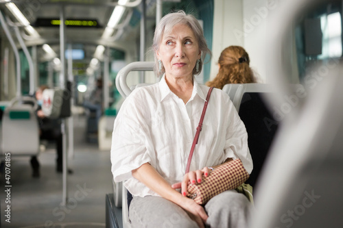 European senior woman sitting on her seat in tram and waiting for next stop.