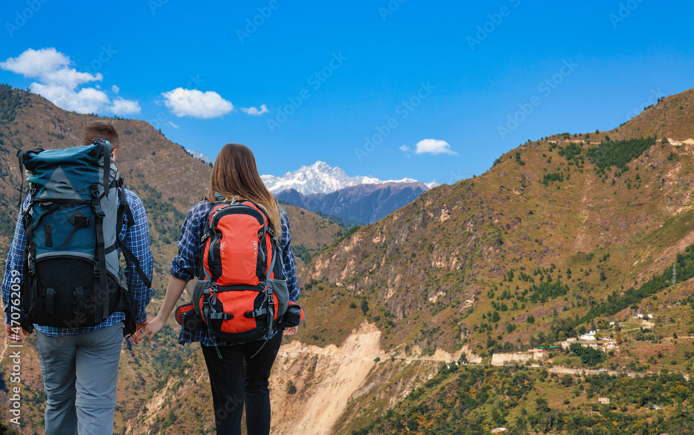 Tourist couple hikers enjoy view of scenic Himalaya mountain landscape at Chitkul Himachal Pradesh, India