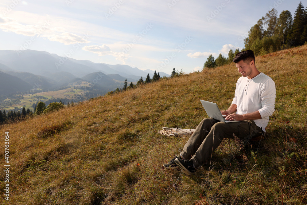 Man working with laptop outdoors surrounded by beautiful nature. Space for text Man working with laptop outdoors surrounded by beautiful nature. Space for text