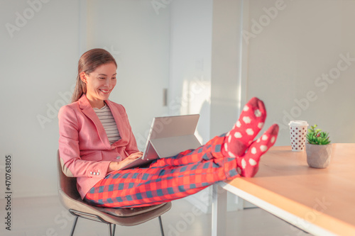 Working from home Asian woman streaming videoconference online in pajamas with suit blazer for remote work. Funny pandemic lifestyle concept photo
