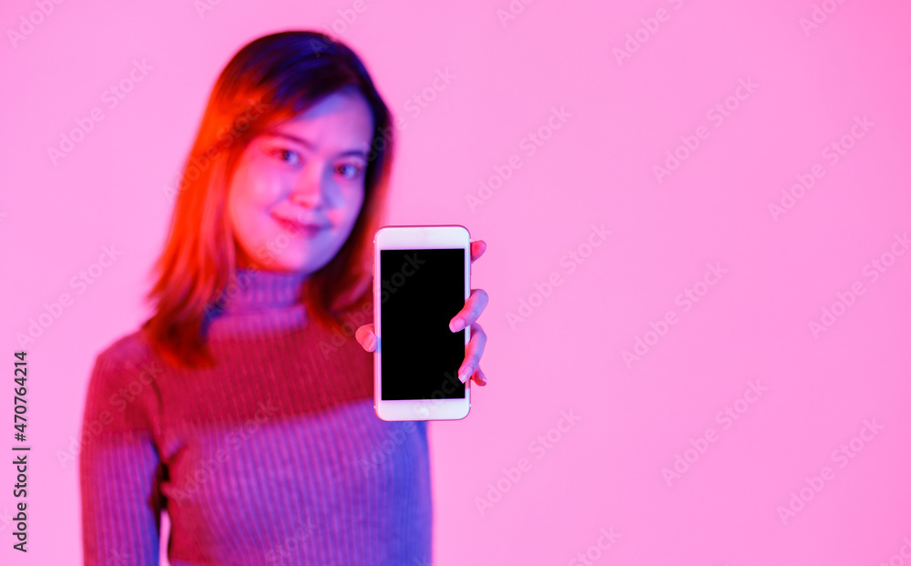 Closeup studio shot of empty black blank screen touchscreen smartphone for advertising in Asian young female model in gray turtle neck sweater hand look at camera on pink light blurred background Closeup studio shot of empty black blank screen touchscreen smartphone for advertising in Asian young female model in gray turtle neck sweater hand look at camera on pink light blurred background