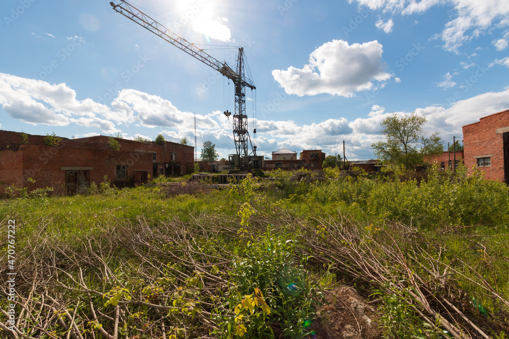 abandoned factory area with brick buildings and a crane in summer abandoned factory area with brick buildings and a crane in summer