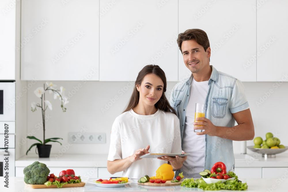 Young happy couple is enjoying healthy meal in kitchen at home.