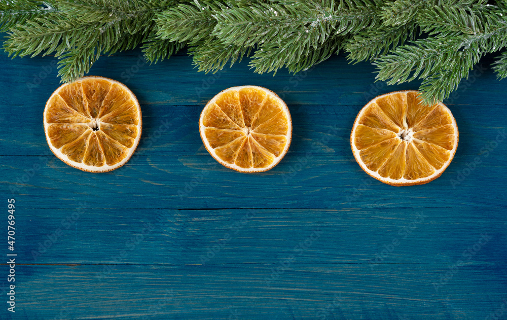 New Year's composition of dried orange slices and artificial spruce branches on a blue wooden background with a place for the text top view New Year's composition of dried orange slices and artificial spruce branches on a blue wooden background with a place for the text top view