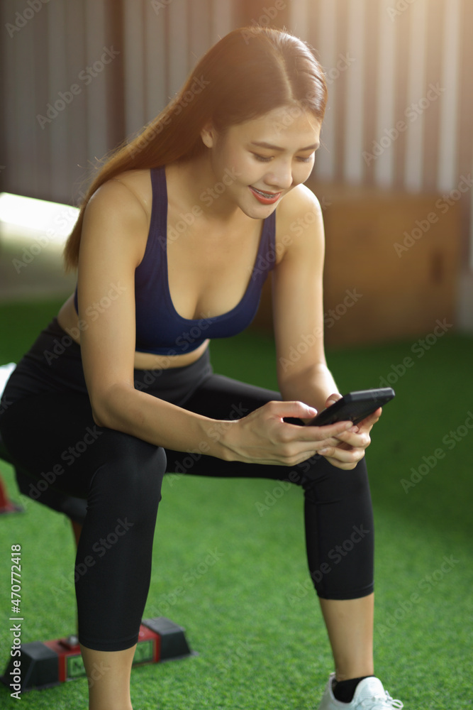 Healthy fit girl sits in the health club using modern mobile phone. Healthy fit girl sits in the health club using modern mobile phone.
