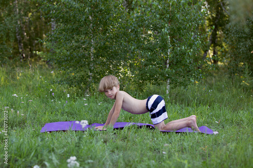 Boy working out, fitness training, bend in cat cow yoga posture. Practices yoga asana marjariasana photo