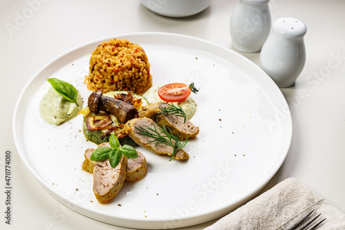 Fototapeta Naklejka Na Ścianę i Meble -  Baked turkey fillet and vegetables with spices. Slices cooked Turkey meat, zucchini with mushrooms, bulgur garnish. Delicious and healthy food. Table setting on a light background. Vertical shot
